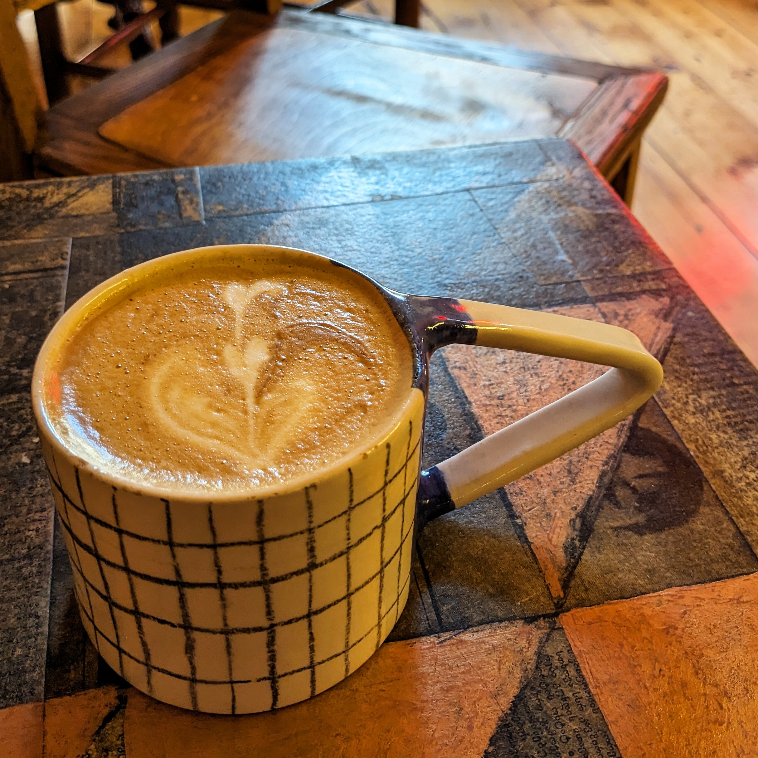 Flat White coffee in a ceramic mug on a wooden table at Eleven Window, one of the best cafes in Tbilisi