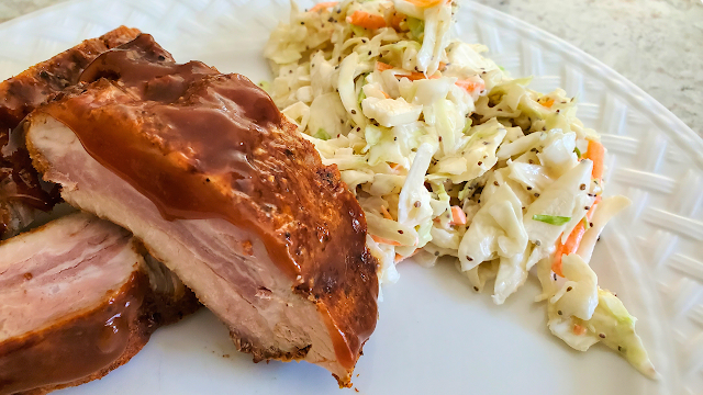 Baby Back ribs on a white plate with coleslaw.