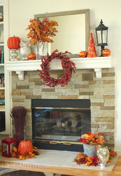 A gorgeous fall mantel in oranges and reds with accent pops of silver and black.  I love how the wreath is hung off the front of the mantel shelf! 
