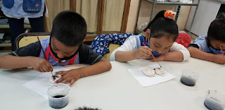 Una niña y un niño cada uno concentrado en la tarea de pintar la pieza de cerámica