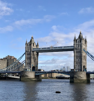 Picture of  Tower Bridge in London, on a bright sunny day with blue sky and Canary Warf in  the background