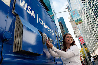 Photo of a woman standing next to a Visa Chase sign.