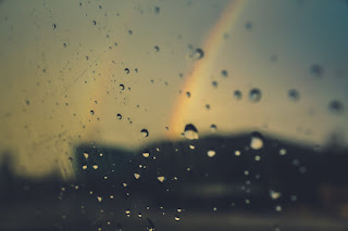 rain on window with rainbow beyond