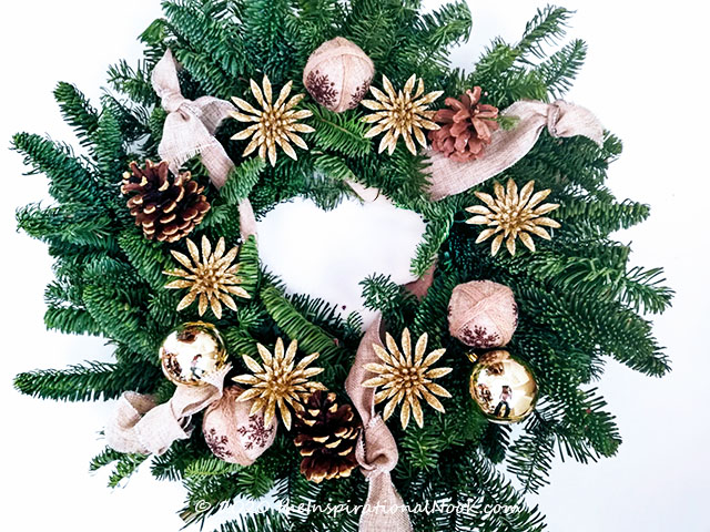 Christmas holiday wreath with gold ornaments, pine cones and burlap ribbon.