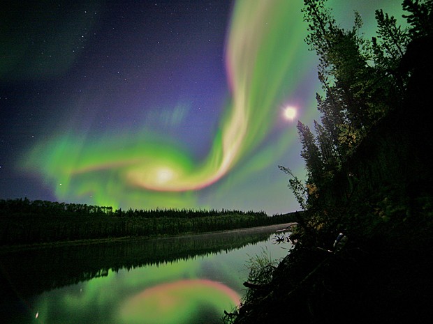 Sob as luzes da aurora boreal, elevam-se os olhares para o céu, pondo-se a contemplar um fenômeno de rara beleza e mistério.