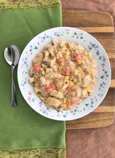 Serving bowl of chicken, corn, and rivel soup.