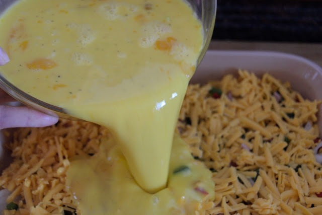 The egg mixture being poured over the ingredients in the casserole dish. 