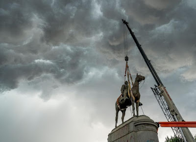 photo of crane removing statues of Stonewall Jackson against cloudy sky