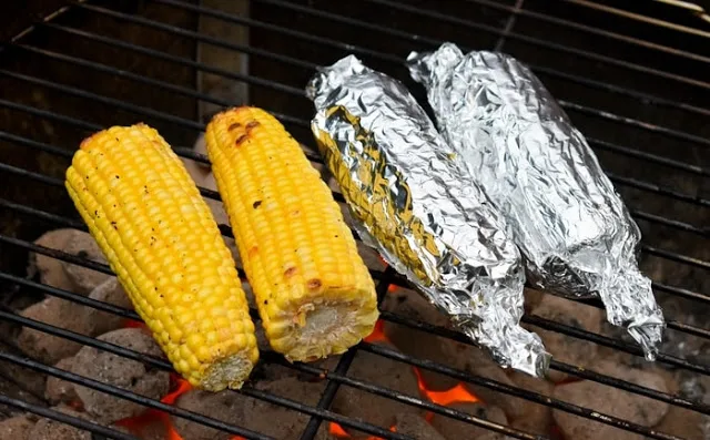 corn on the cob on a BBQ two in foil and two naked