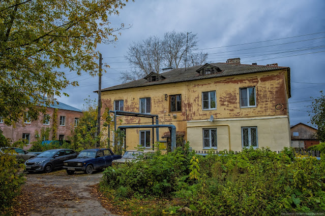 Припаркованные машины у старого двухэтажного здания