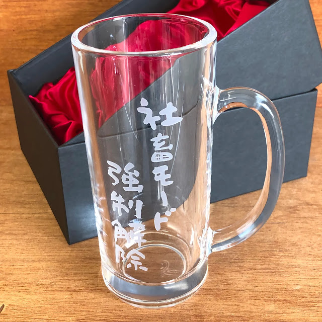 「社畜モード強制解除」の文字が刻まれたビールジョッキ。赤い布入りの黒いギフトボックスにセットされている。