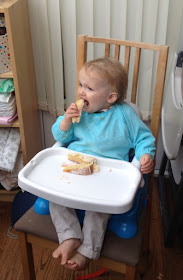 baby eating cake sat in high chair