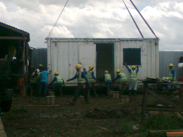 Human labor placing the container van on top of the pedestal