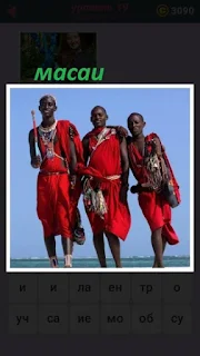 стоит трое мужчин масаи в красной одежде