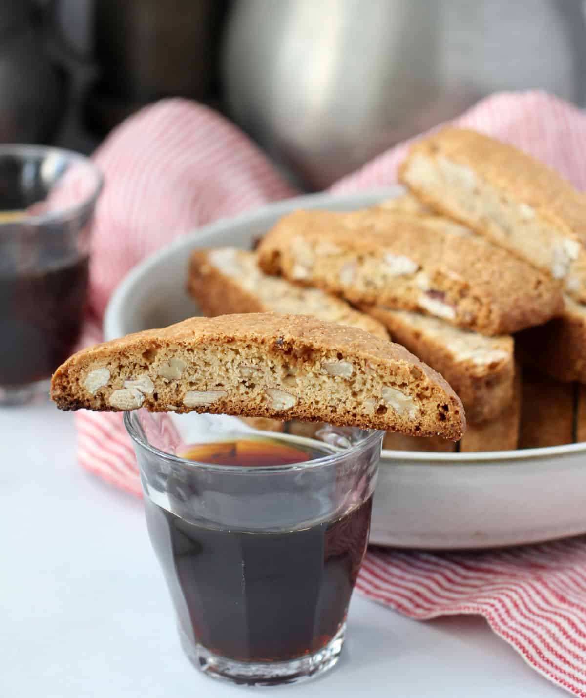 Maple Pecan Biscotti with a slice on top of a glass of coffee.