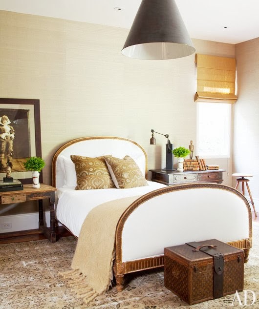 Bedroom with a Louis Vuitton Trunk at the foot of the bed and a large cone shaped pendant light