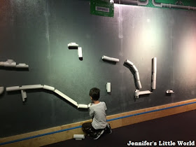 Child playing with pipes along the wall