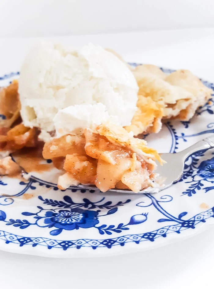 flaky apple pie slice, vanilla bean ice cream, blue floral plate