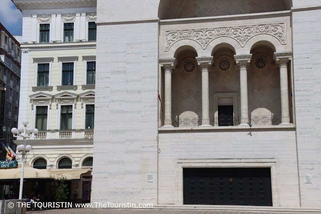 A large square-built white property with three intricately decorated pillars.