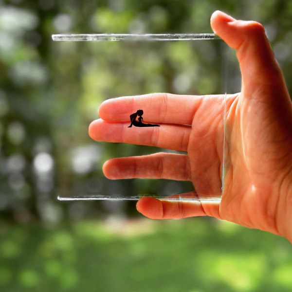 Hand holds square net frame with miniature silhouette in yoga pose.