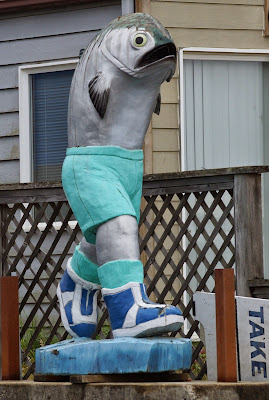 carving of a walking salmon in shorts and sneakers