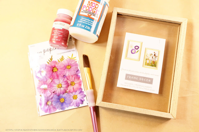 Frame decor with paper flowers, Mod Podge, and paintbrush on a table