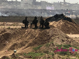 three IDF soldiers look at Gaza from the border