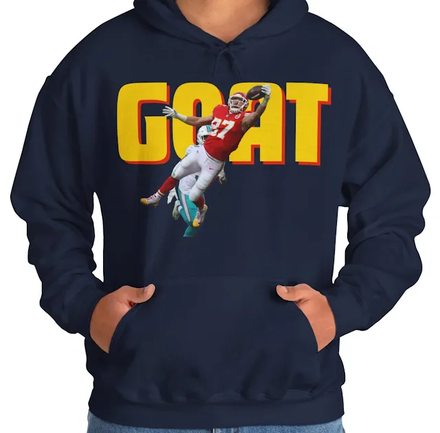 A Hoodie With NFL Player Travis Kelce In The Air Holding the Duke and the Text GOAT in The Background