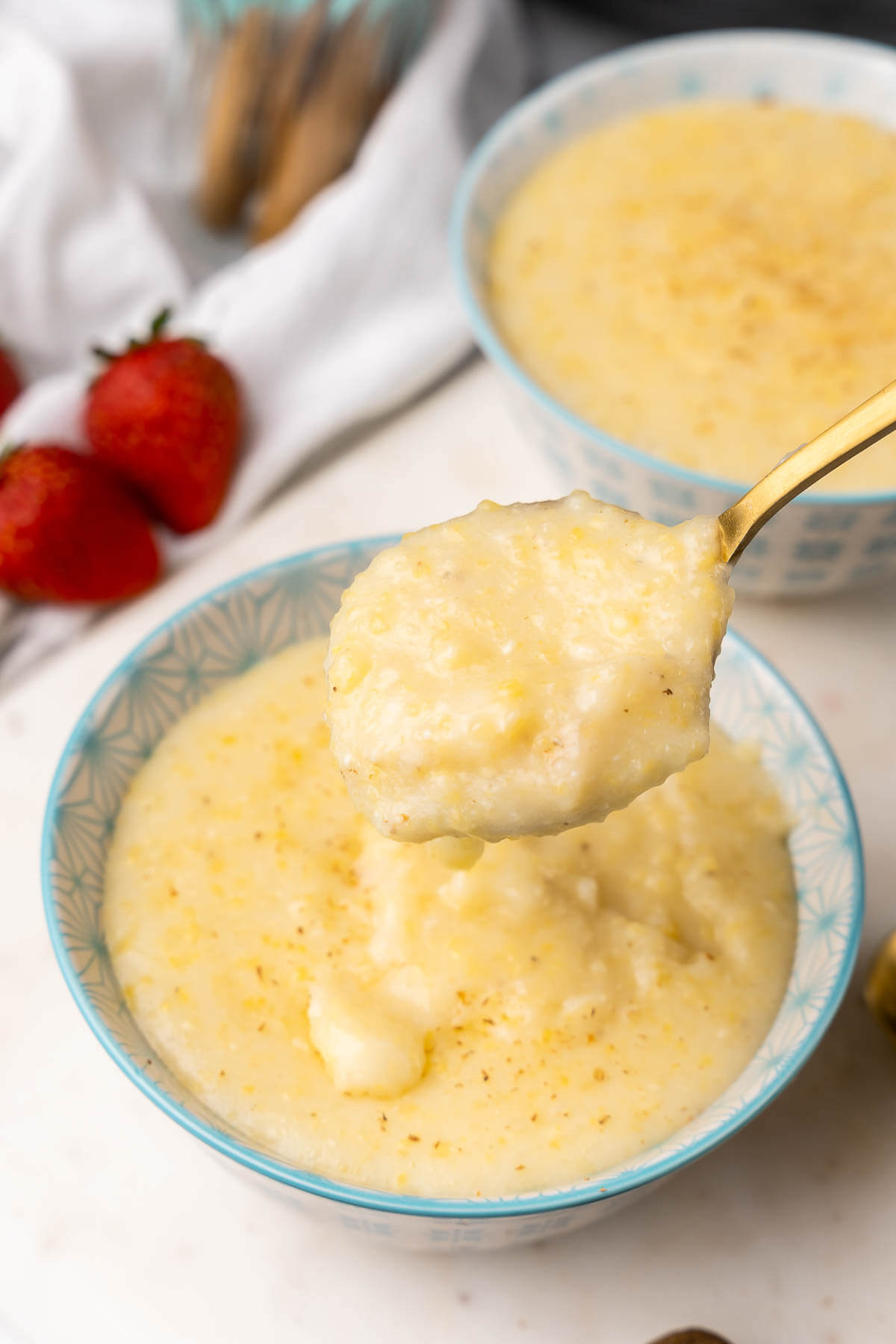 A spoonful of cornmeal porridge over a bowl serving.
