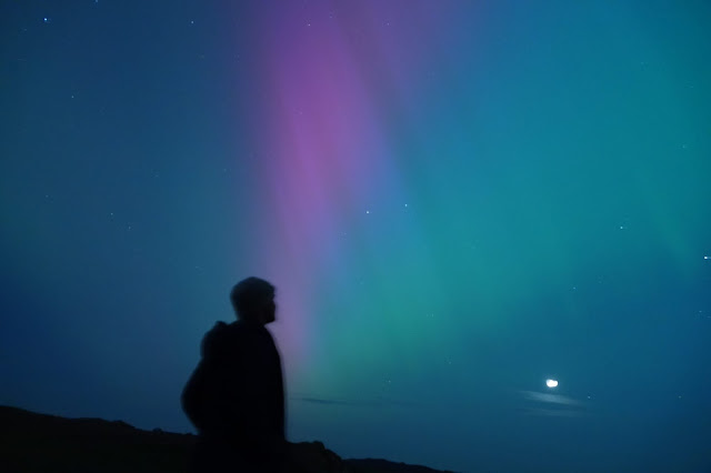 A single figure silhouetted against the northern lights