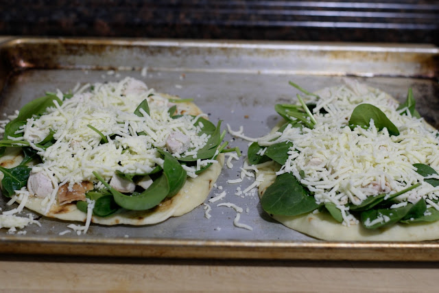 Shredded mozzarella cheese on the naan bread pizza crusts.