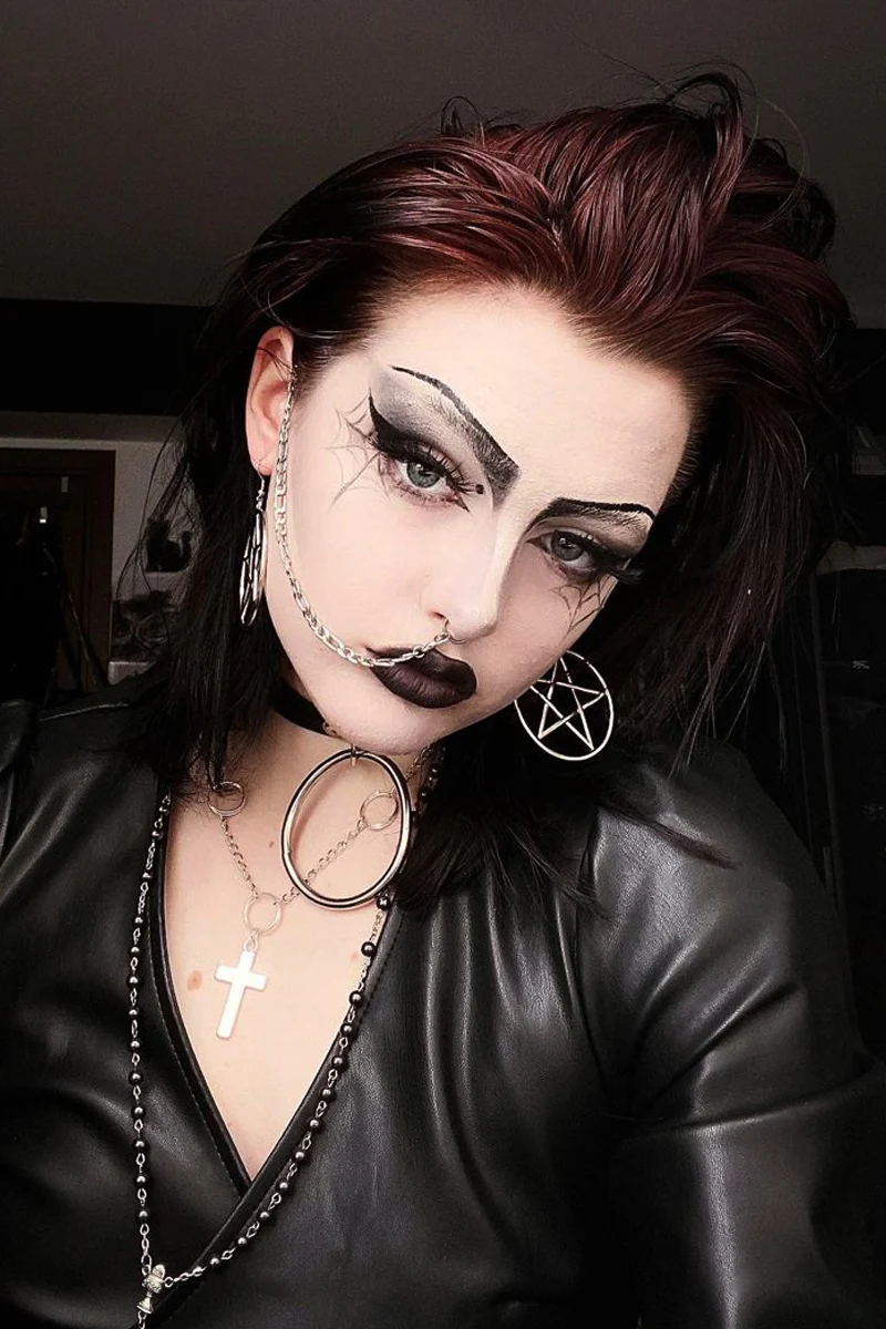 portrait of a young woman with black hair and industrial goth outfit and makeup