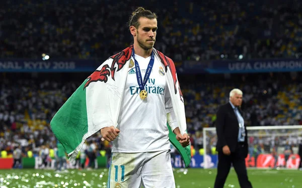 Gareth Bale of Real Madrid walks off the pitch with a Wales flag drapped over him after the UEFA Champions League Final between Real Madrid and Liverpool at NSC Olimpiyskiy Stadium on May 26, 2018 in Kiev, Ukraine