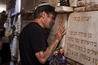 man-cries-beside-a-memorial-stone