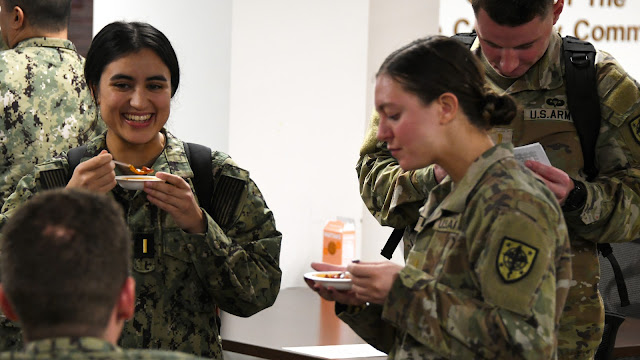 Medical student Navy Ensign Elisabeth Kaza samples chili at the Enlisted Social Committee cook-off event, which drew a large crowd of volunteer judges to the competition. (Photo credit: Ian Neligh, USU)