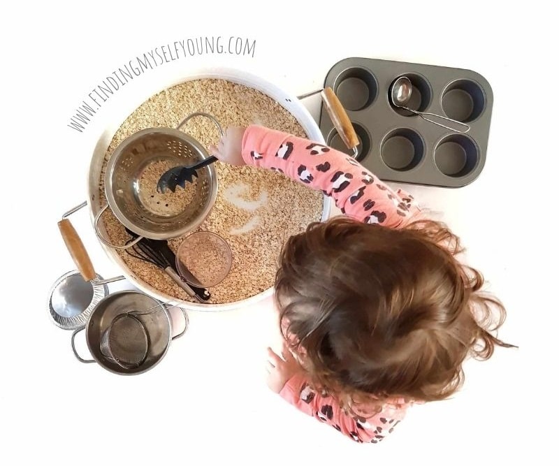 oat sensory bin with pots and pans.