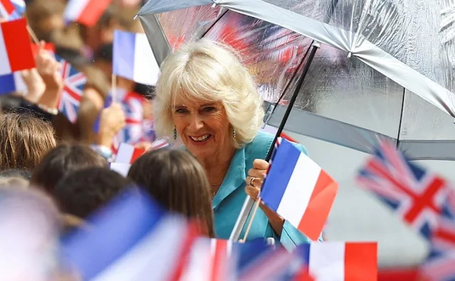 Queen Camilla wore a blue dress coat, and floral print midi dress. Diamond brooch. HMS Iron Duke