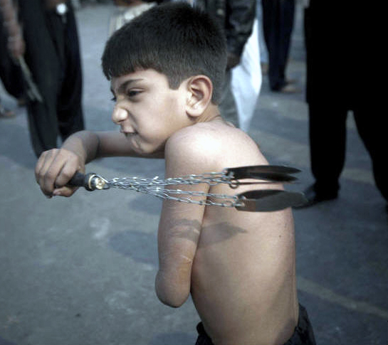 Pakistani Shiite Muslim boy flagellates himself with knifes during a 