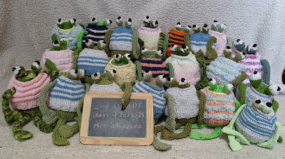 a photo of knitted frogs in sweaters posing as a school class photo