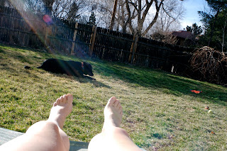 feet sunning in a backyard with a dog