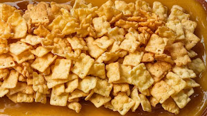"Sticky cornflake mixture being spread over the syrup layer on the tart."