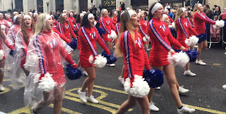 Pic of cheerleaders in wet weather gear singing loudly as they walk