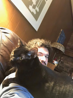 A large black cat sitting on a bearded man's shoulder. (me)
