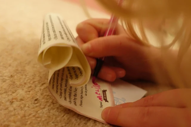 Close up of the fairy lease agreement and a young girl writing her name with a pink pen