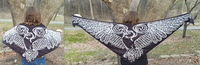 a person facing trees and grass, spreading their arms out to show a white and black shawl patterned like a bird with outspread wings