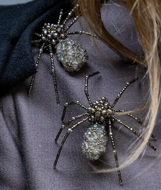 Queen Maxima wore a gray jacket by Natan. Celedonio spider brooch. Natan gray wide leg trousers