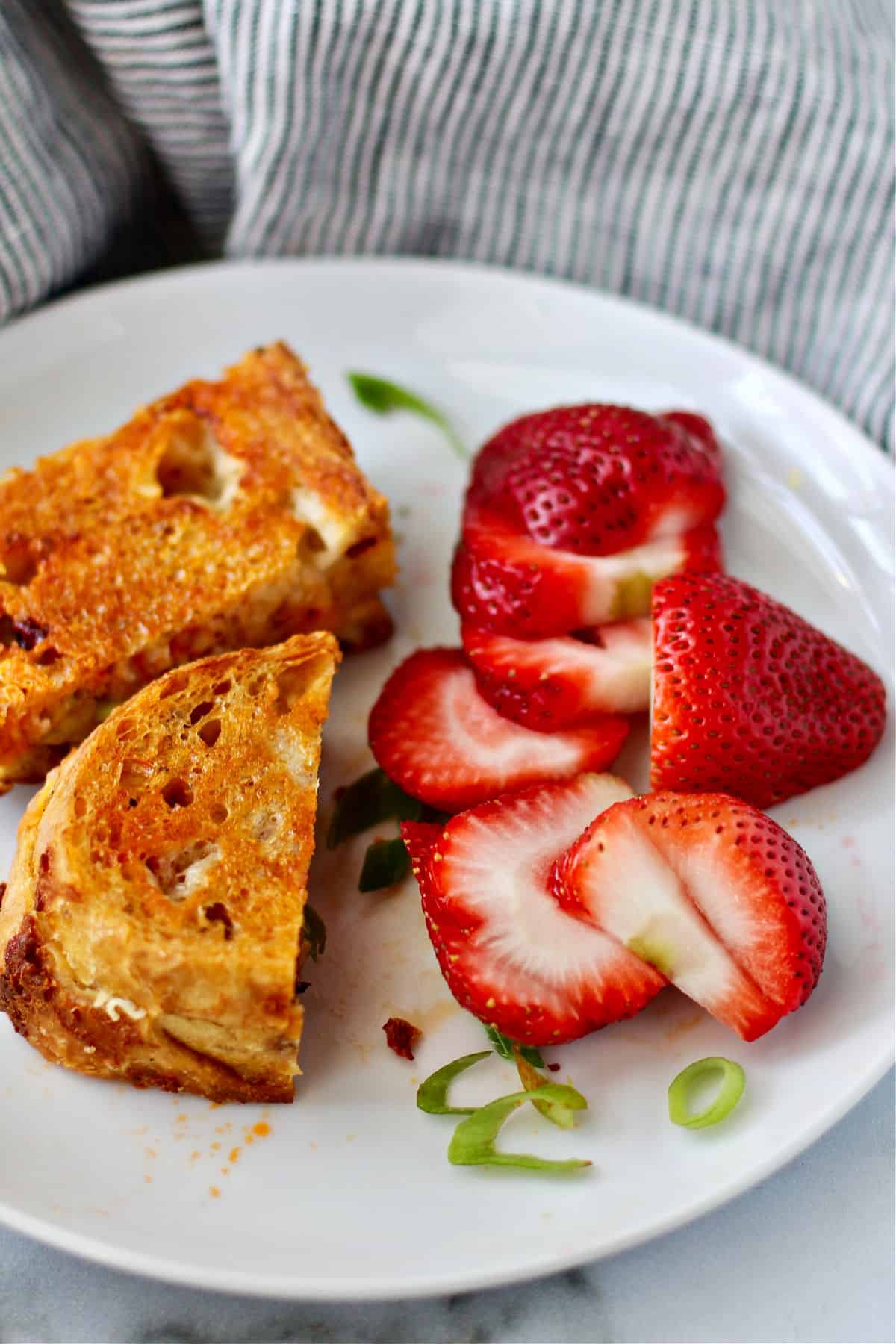 Chili Crisp Grilled Cheese with strawberries on a plate.