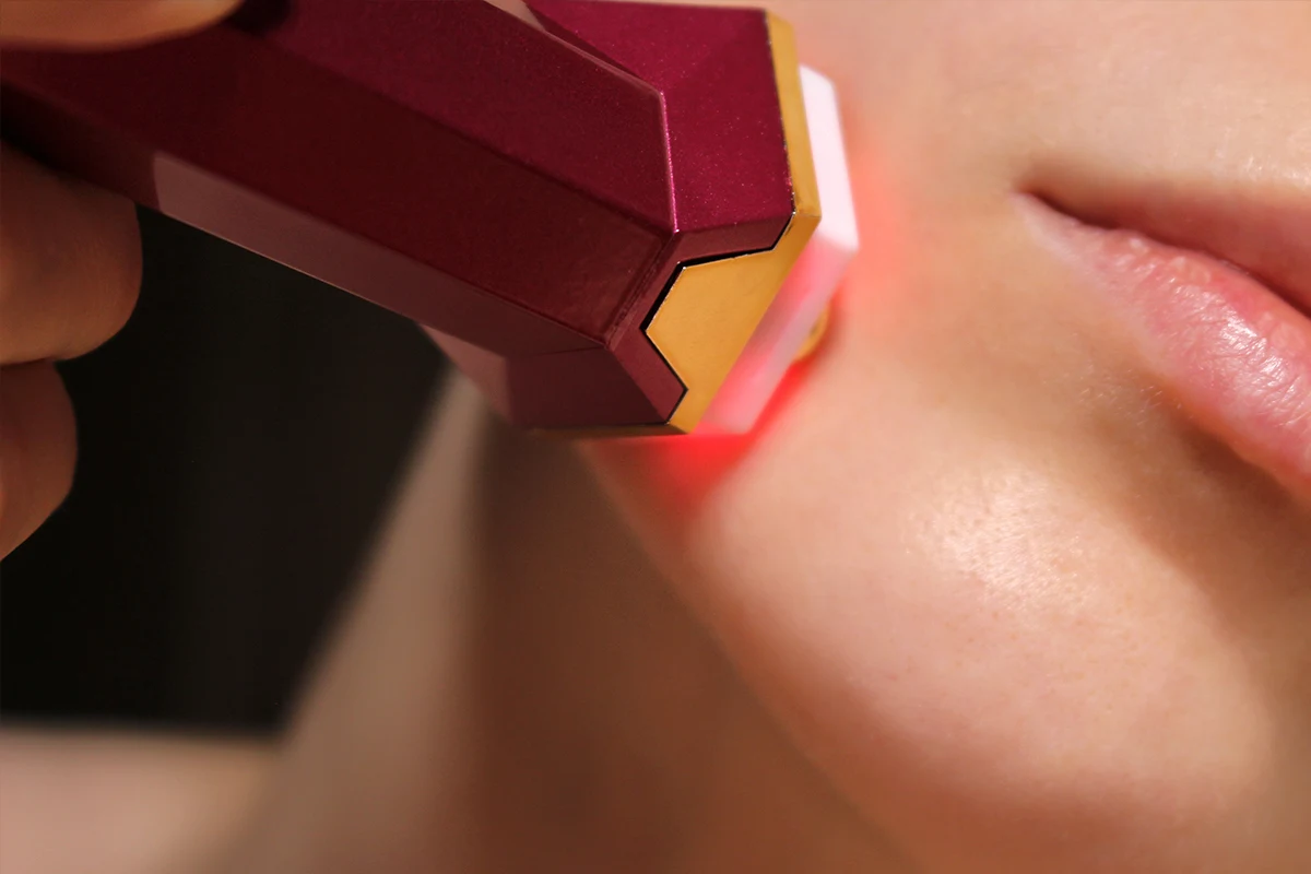 close-up of a female face using a portative facelift device on her skin