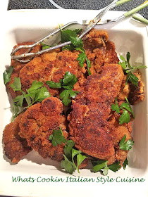 This is a steak coated with breading and fried with delicious Italian spices with parsley garnished on top in a white dish