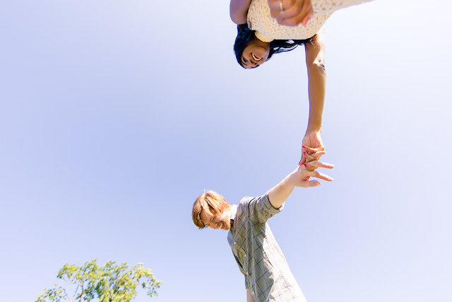 Engaged couple walking holding hands and laughing; shot from below looking up at their faces.